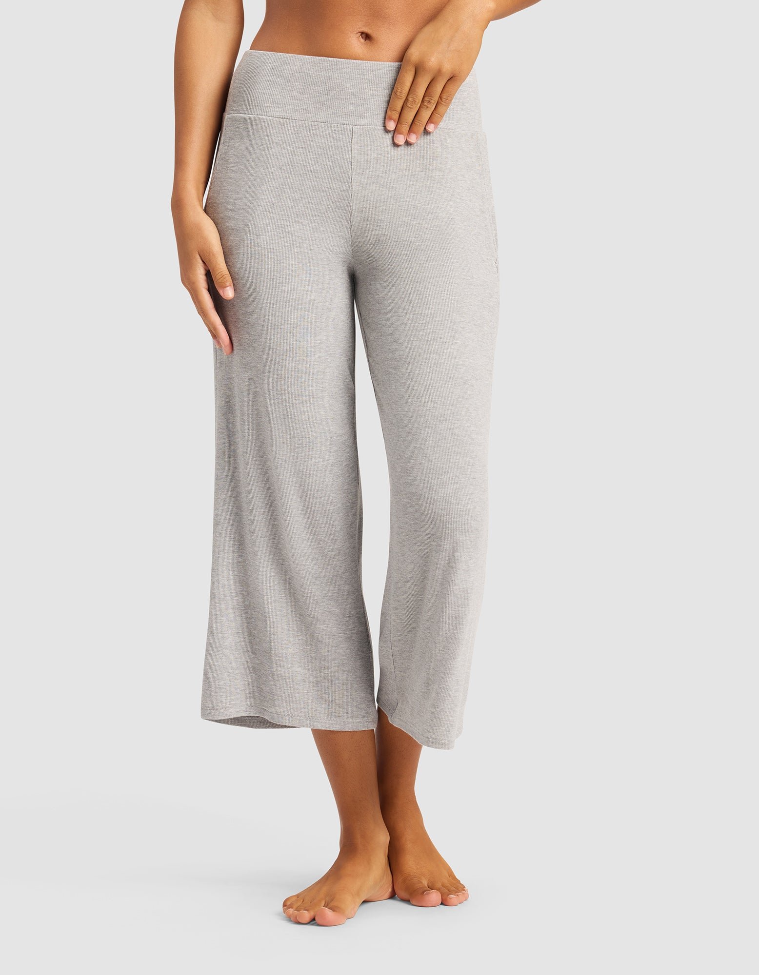 A person models the Cozy Earth Women’s Bamboo Rib-Knit Lounge Capri in light gray, standing barefoot against a plain white background with their left hand on their hip. The upper body is partially out of frame.