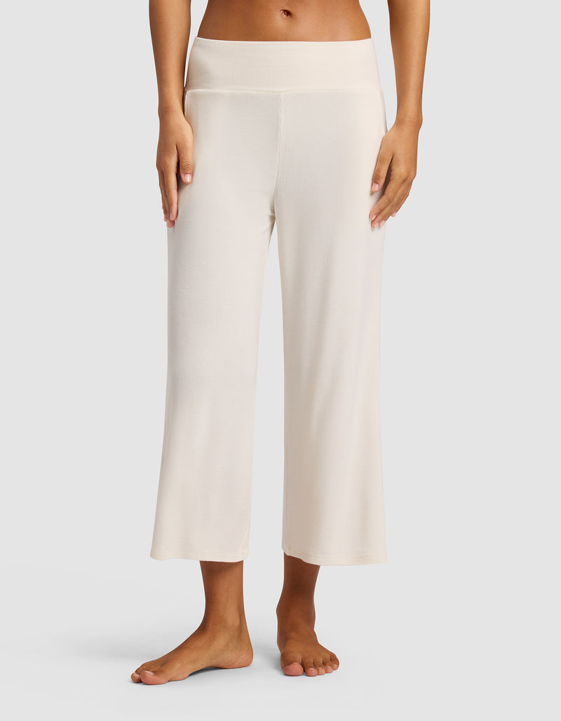 A woman stands barefoot against a plain backdrop wearing Cozy Earth’s Women’s Bamboo Rib-Knit Lounge Capri in Ivory, featuring wide-leg, cropped design, high waistband, and relaxed fit.