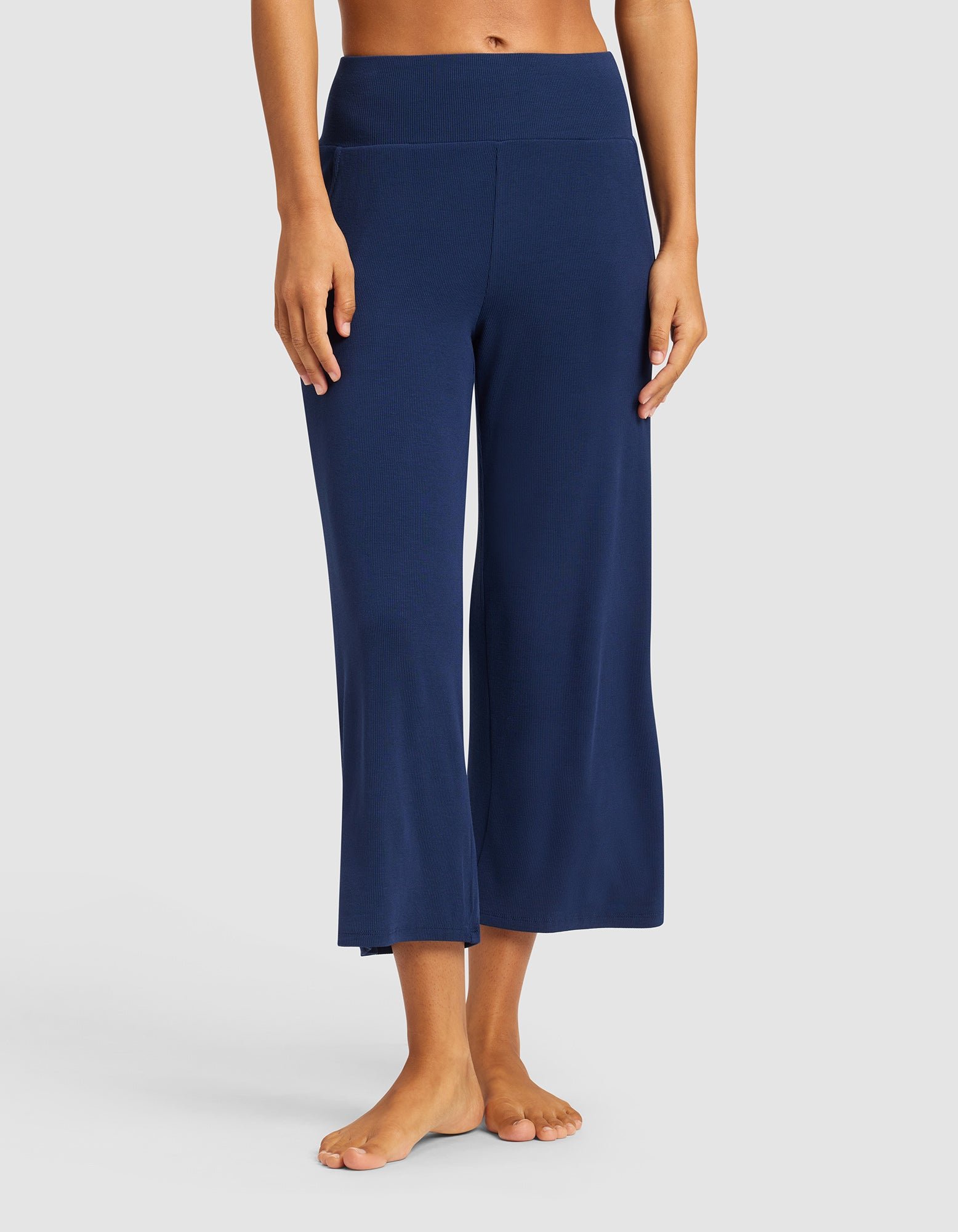 A person stands barefoot against a plain light background wearing Cozy Earth's Women’s Bamboo Rib-Knit Lounge Capri in navy; only their upper body and feet are partially visible.|Color:Navy