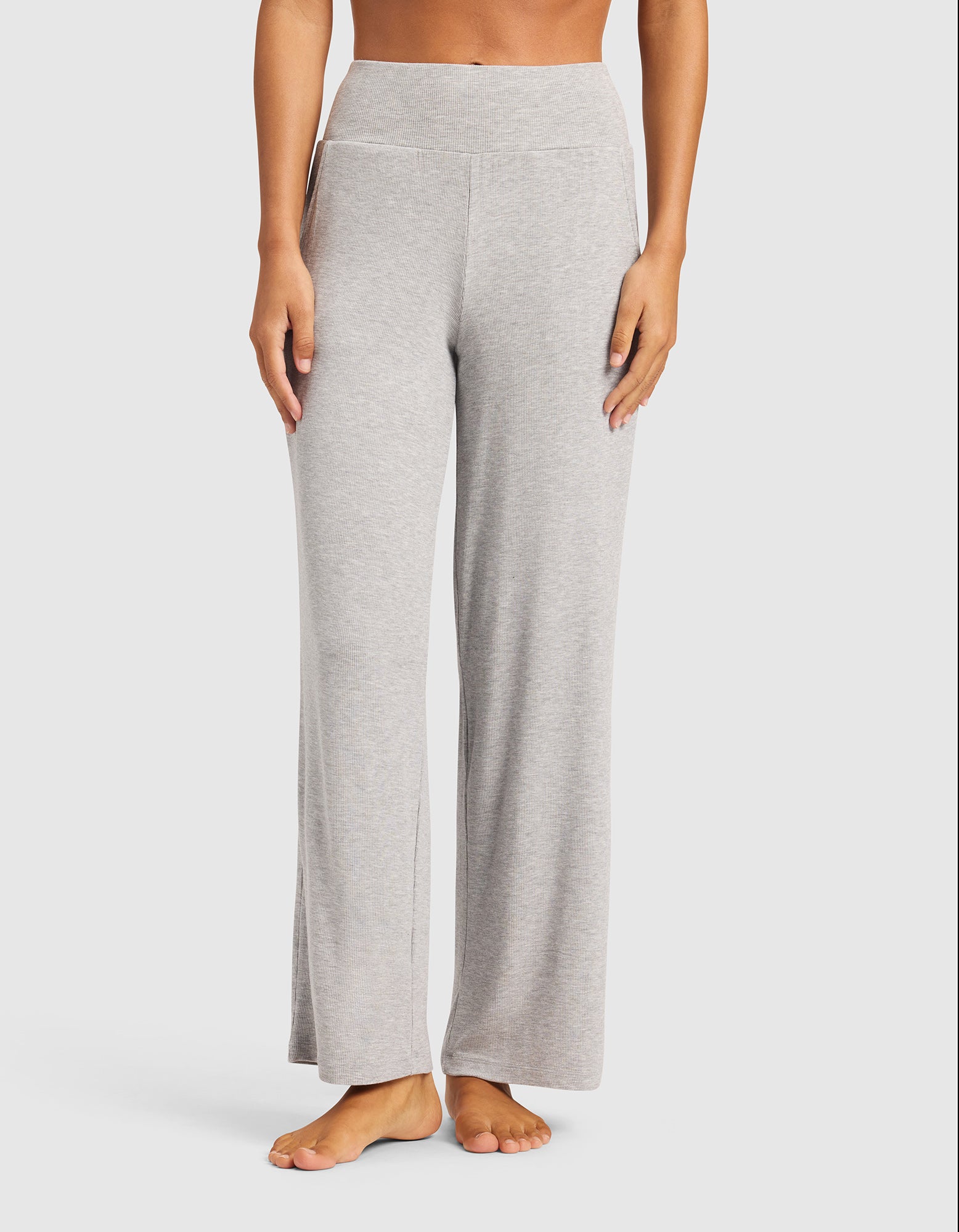 A person stands barefoot wearing Cozy Earth Women’s Bamboo Rib-Knit Lounge Pant in light gray. The high-waisted, wide-leg pants are shown from waist to feet against a plain white background.