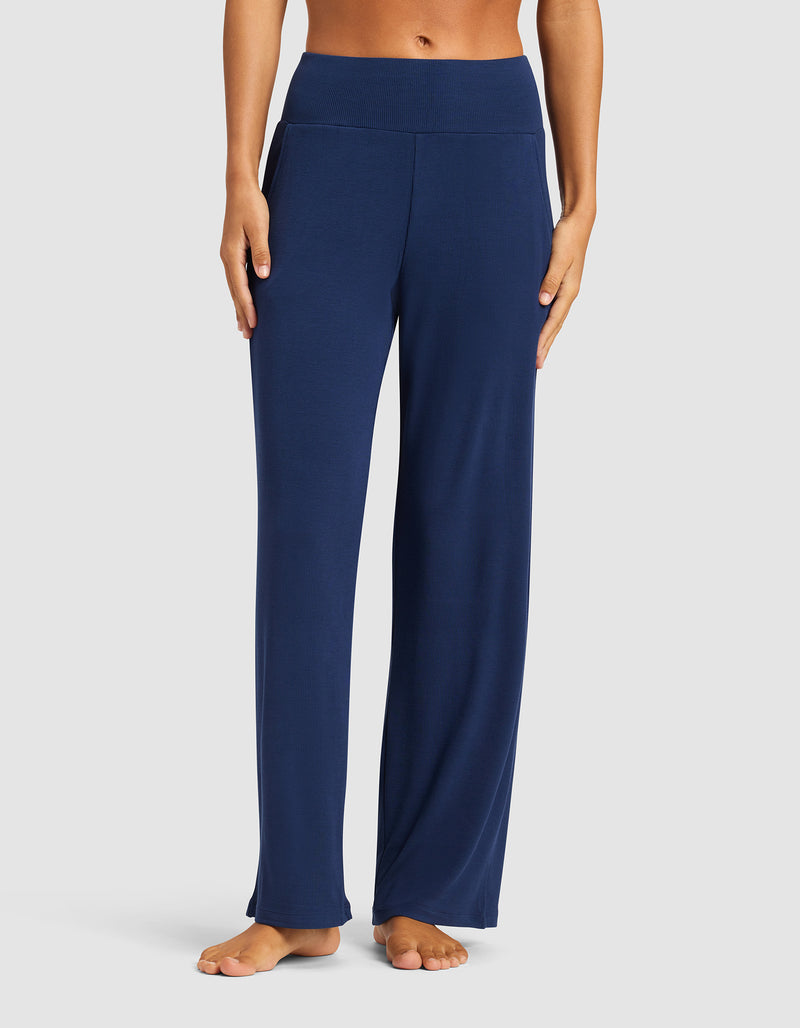 A person stands barefoot against a plain background, wearing Cozy Earth Women’s Bamboo Rib-Knit Lounge Pant in navy blue, featuring a wide waistband and relaxed fit.
