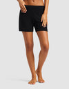A person, barefoot against a plain background with a hand on their hip, models Cozy Earth’s Women’s Bamboo Rib-Knit Lounge Short in black. Only the lower body is visible.|Color:Black