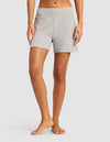 A person stands barefoot, shown from the waist down, wearing light gray Cozy Earth Women’s Bamboo Rib-Knit Lounge Shorts with a matching waistband against a plain white background.|Color:Grey