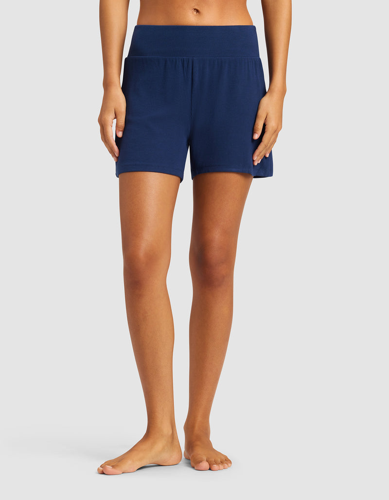 A person stands barefoot against a plain background, showing only the lower half of their body while wearing Cozy Earth's Women’s Bamboo Rib-Knit Lounge Short in navy.