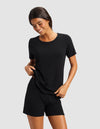 A dark-haired woman smiles and looks down against a light background, wearing the Cozy Earth Women’s Bamboo Rib-Knit Short Sleeve Lounge Top in black.|Color:Black
