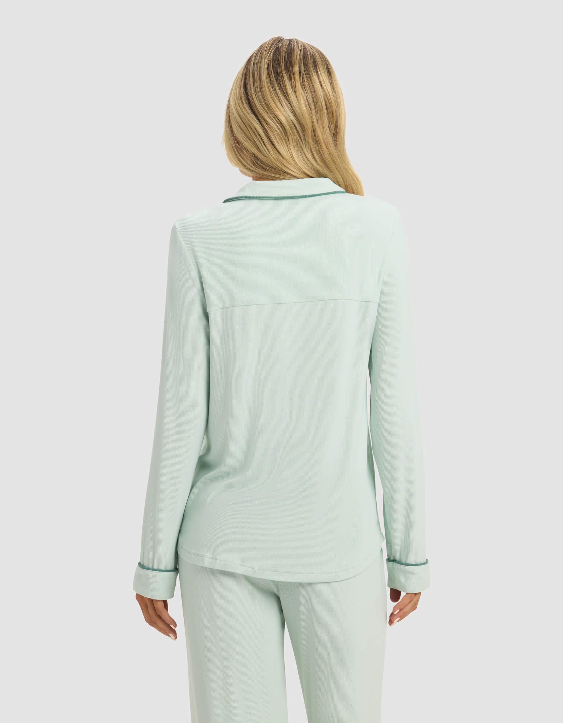 A woman with long blonde hair is shown from the back wearing the Cozy Earth Women's Bamboo Rib-Knit Classic Long Sleeve Pajama Top in light green, standing against a plain white background.|Color:Seafoam