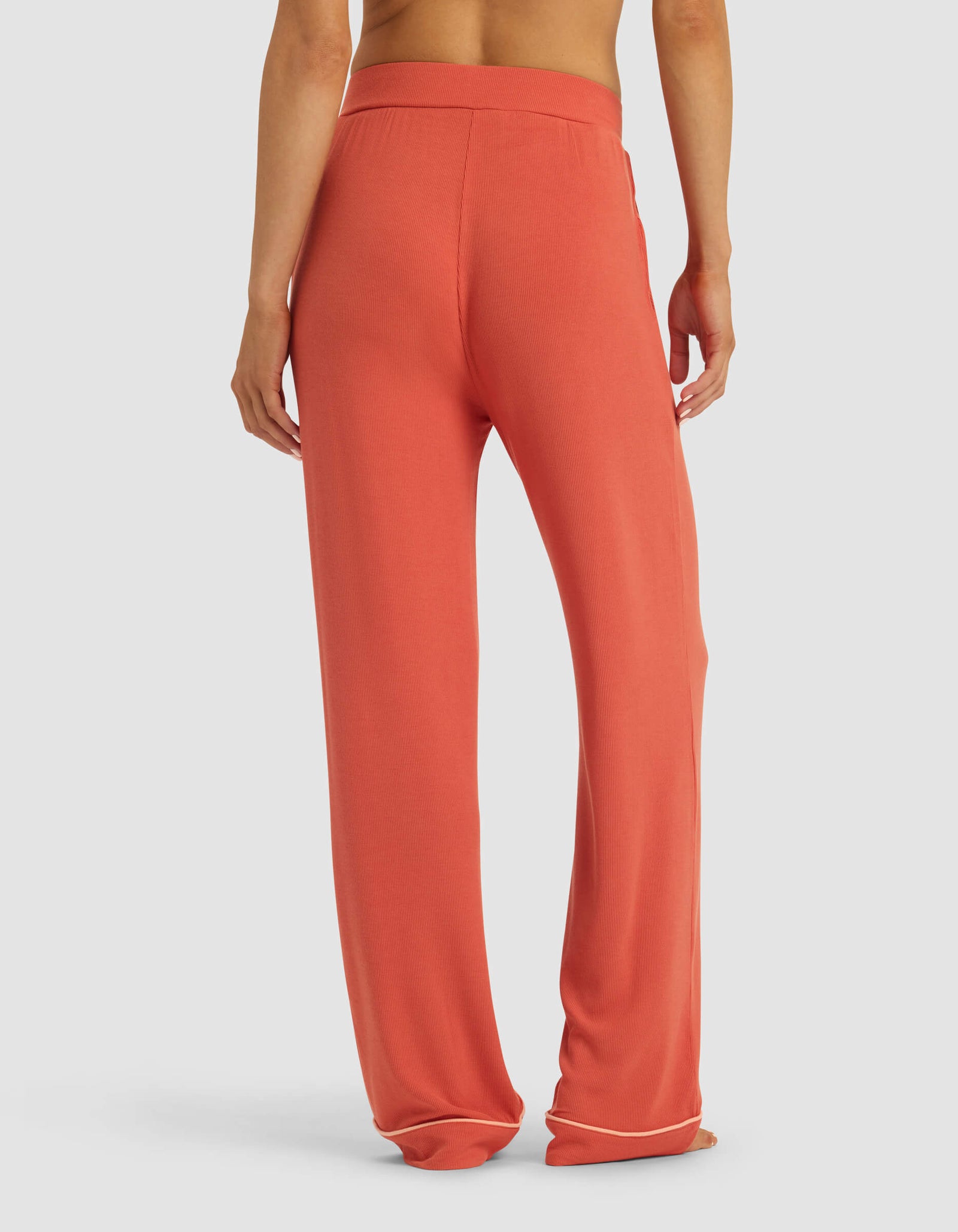 A person faces away, wearing Cozy Earth's Women's Bamboo Rib-Knit Classic Pajama Pant—loose-fitting, high-waisted pants with a wide leg and elastic waistband. Their upper body is bare against a plain white background.