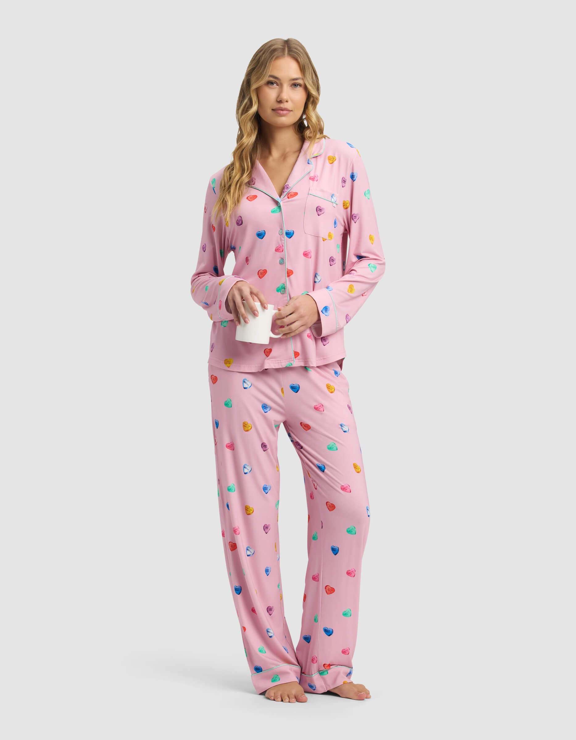 A woman in a Cozy Earth Women's Bamboo Stretch-Knit Long Sleeve Pajama Top stands barefoot with a white mug against a plain light background.
