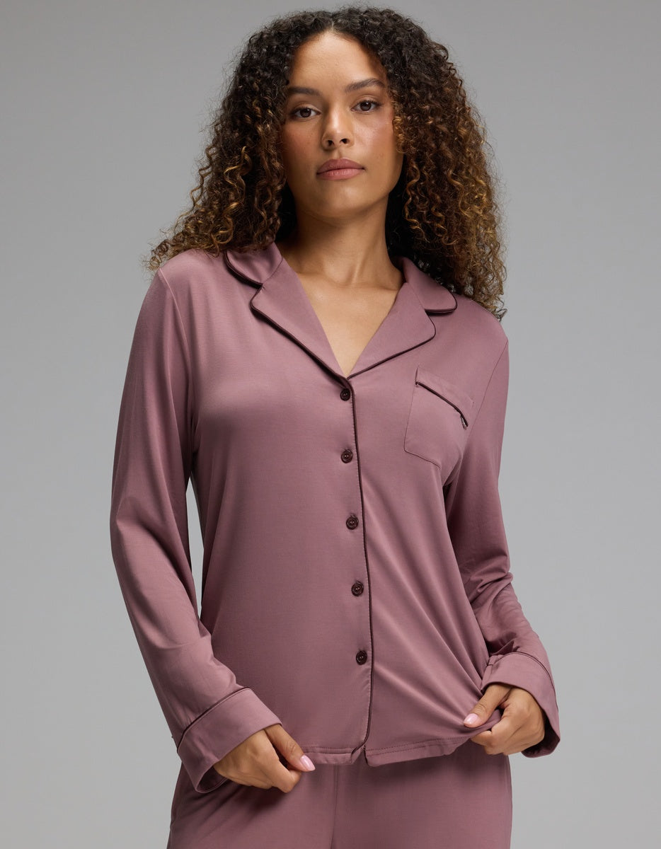 A person wearing a dusty mauve Cozy Earth Women’s Bamboo Stretch-Knit Long Sleeve Pajama Top with a notched collar, button-down front, and a single chest pocket.