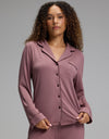 A woman wears a copper rose Women’s Bamboo Stretch-Knit Long Sleeve Pajama Top - Petite, featuring a button-down front, a collar, and a chest pocket.|Color:Copper Rose