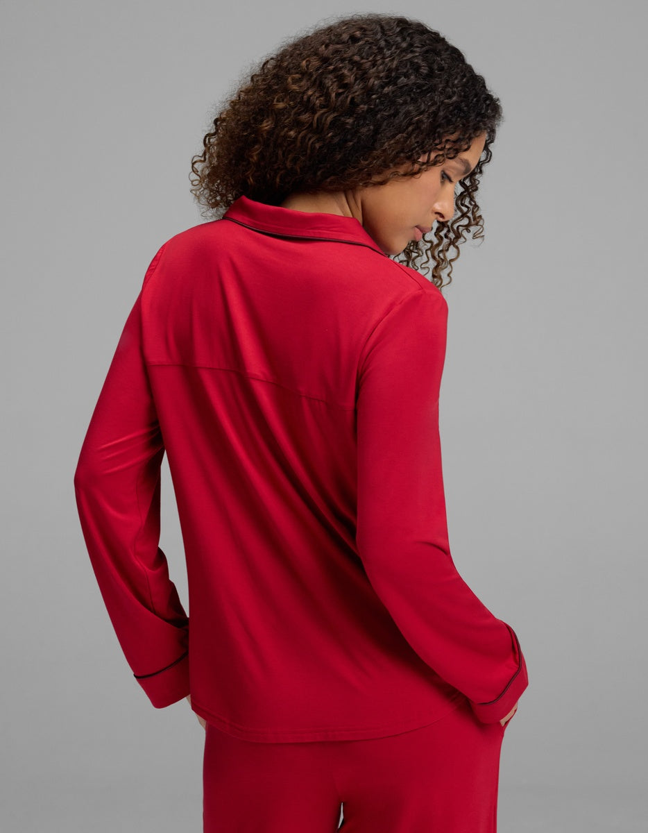 A person seen from the back wearing a red Women’s Bamboo Stretch-Knit Long Sleeve Pajama Top with black trim on the collar and cuffs.