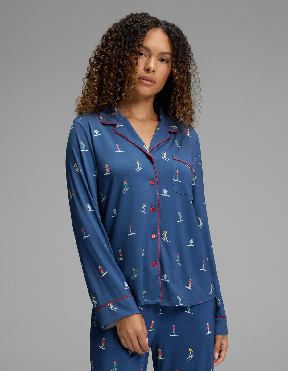 A Cozy Earth Women’s Bamboo Stretch-Knit Long Sleeve Pajama Top in blue, featuring a red-trimmed collar and a print of small skiers.