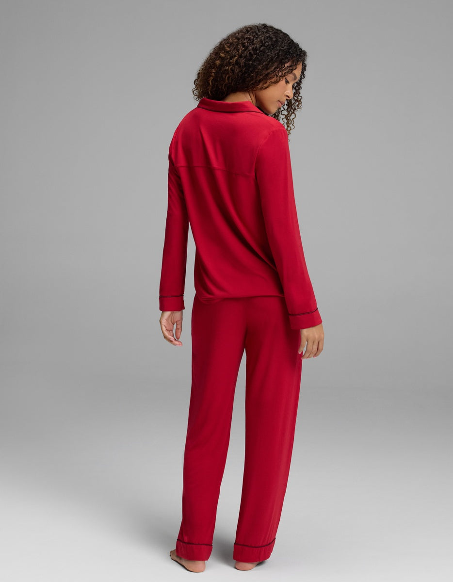 A woman seen from behind wearing a red Women’s Bamboo Stretch-Knit Long Sleeve Pajama Set with black trim.