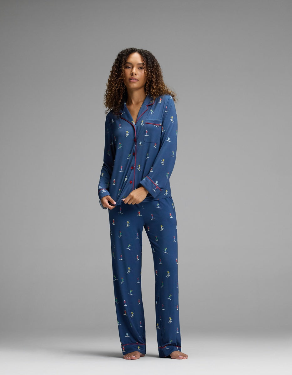 A person wearing a Cozy Earth Women’s Bamboo Stretch-Knit Long Sleeve Pajama Set in blue with a pattern of small figures and red piping detail on the collar and cuffs.