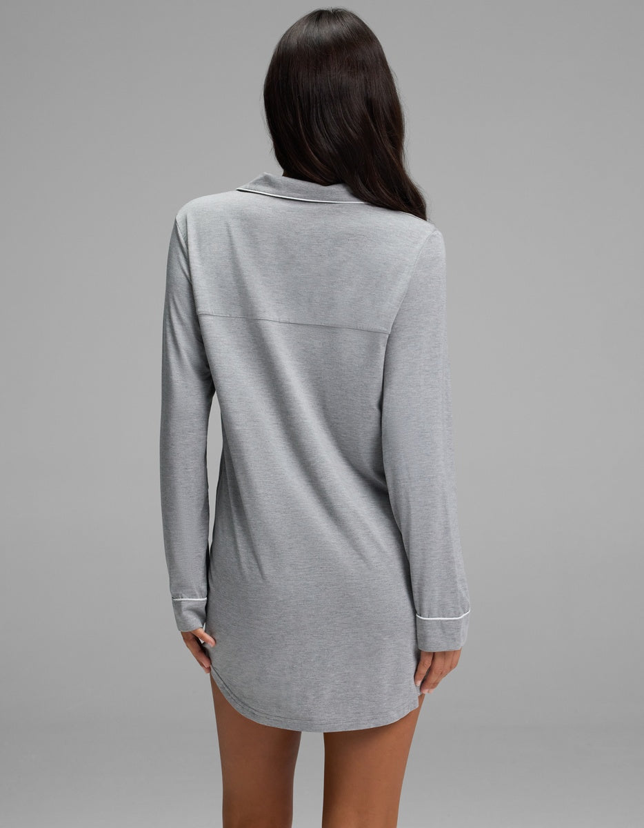 A woman seen from behind wearing a grey Women’s Bamboo Stretch-Knit Long Sleeve Sleep Dress with white piping along the collar and cuffs.