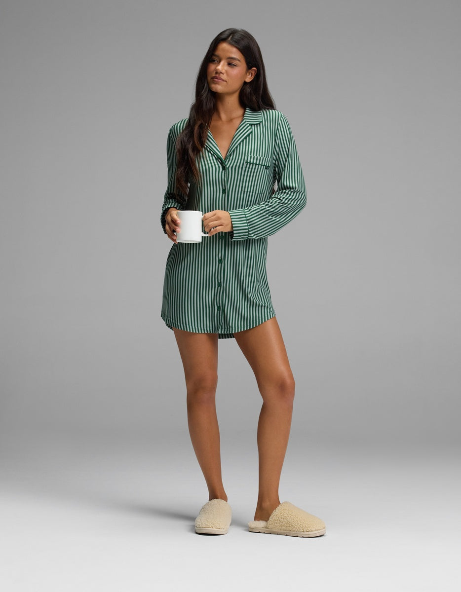 Woman wearing a green-and-black striped Cozy Earth Women’s Bamboo Stretch-Knit Long Sleeve Sleep Dress and beige slippers, holding a white mug.