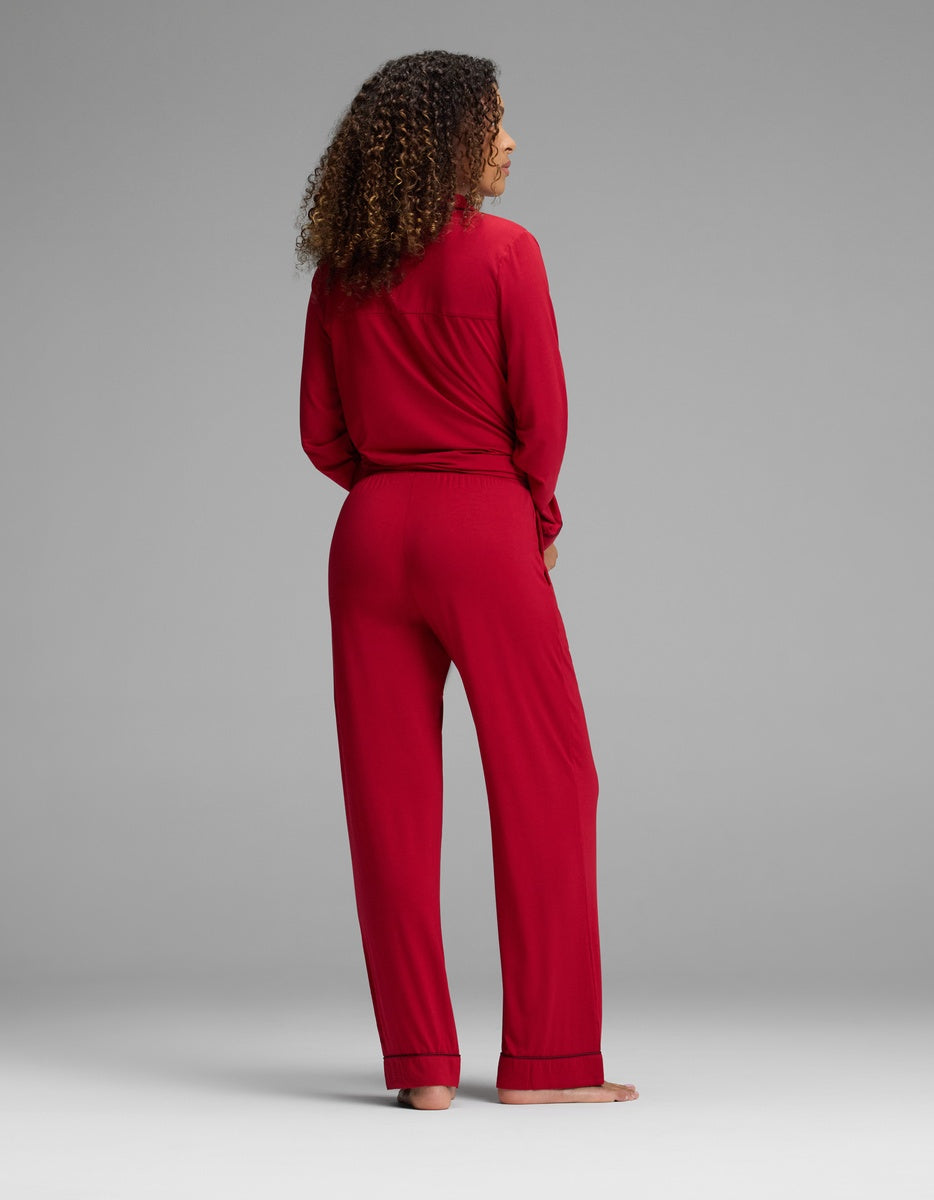 A person viewed from behind wearing a red long-sleeved pajama top and matching Women’s Bamboo Stretch-Knit Pajama Pant with dark trim at the ankles.