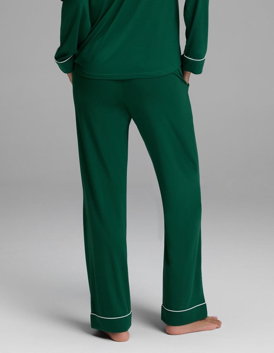 Back view of a person wearing dark green Cozy Earth Women’s Bamboo Stretch-Knit Pajama Pant with white piping at the cuffs.