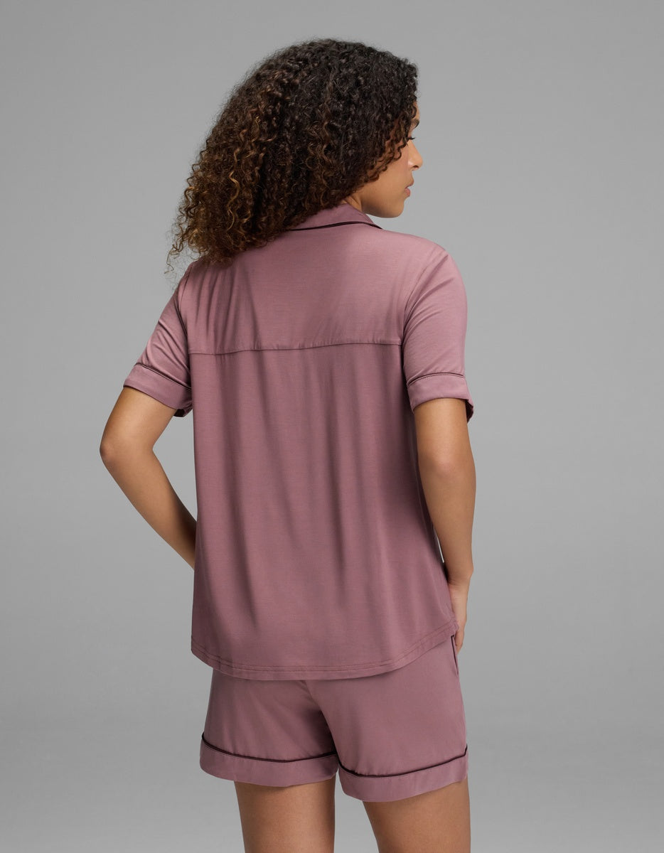 A person seen from behind wearing a mauve Women’s Bamboo Stretch-Knit Short Sleeve Pajama Top and matching shorts with dark piping.