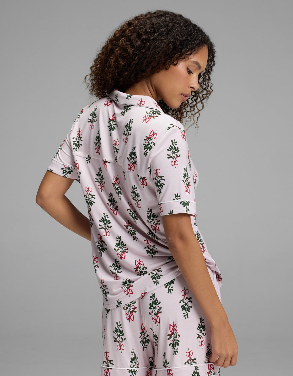 A woman wearing a Cozy Earth Women’s Bamboo Stretch-Knit Short Sleeve Pajama Top in a pink and green floral pattern.