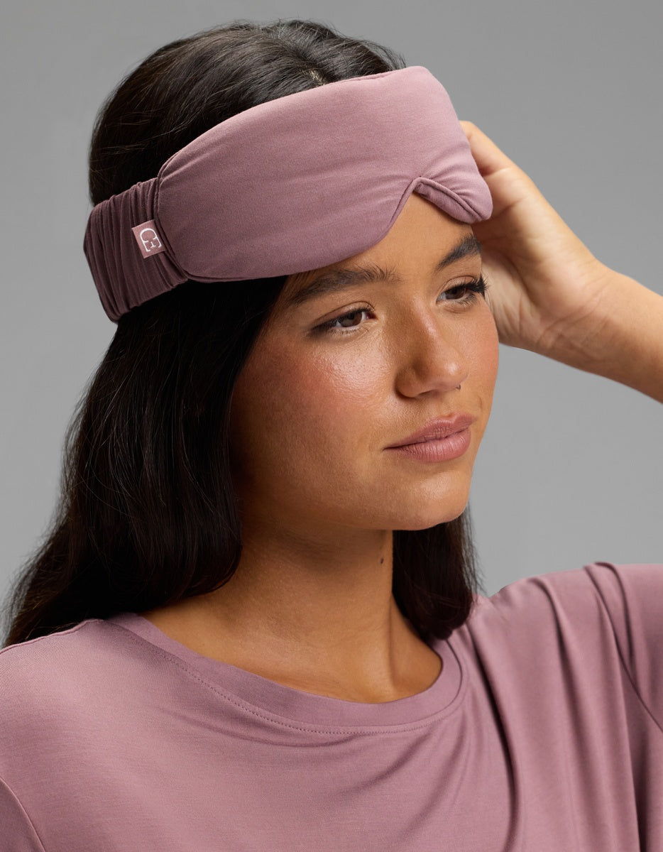 A person wearing a dusty pink Cozy Earth Bamboo Stretch-Knit Sleep Mask on their forehead.