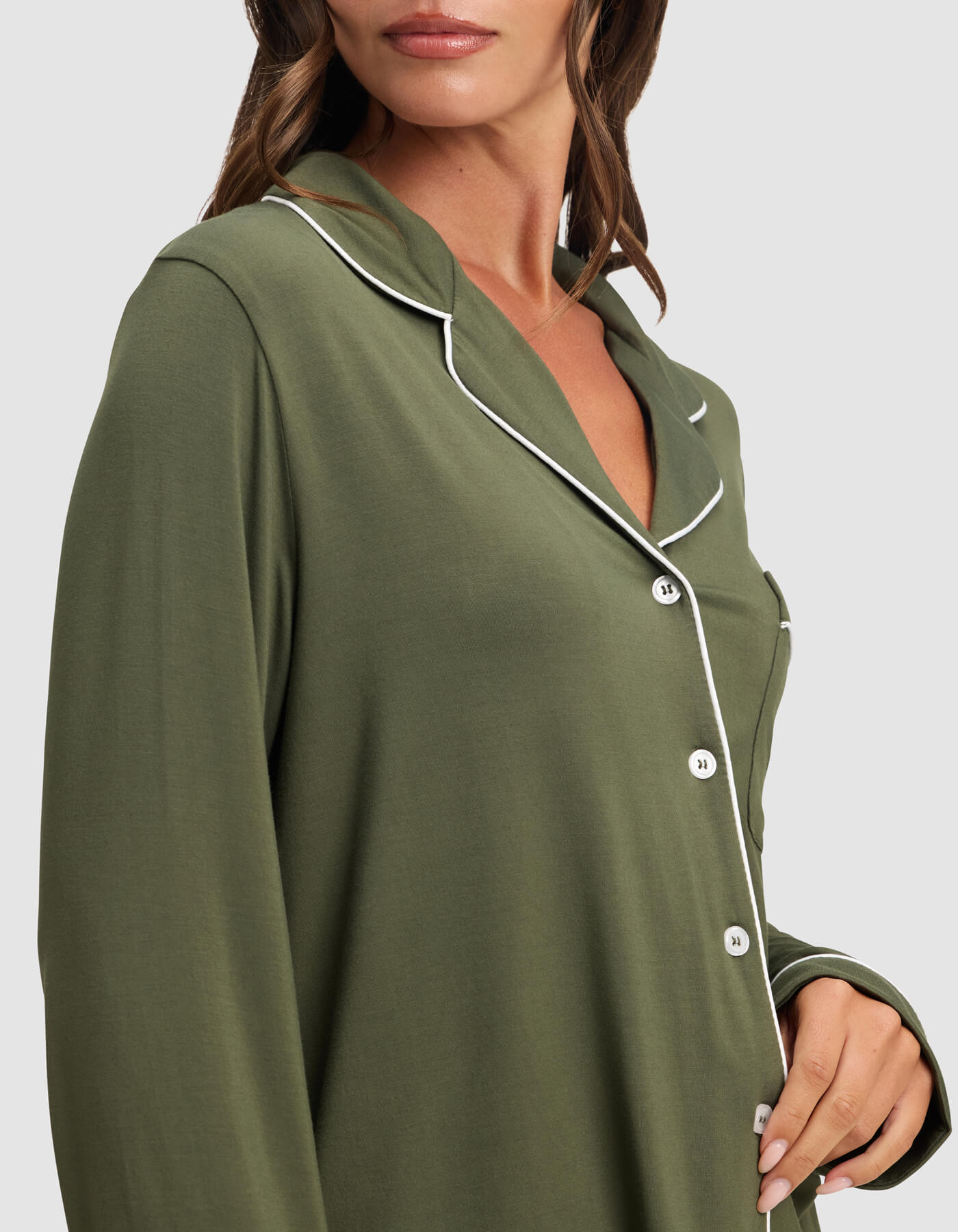 A woman models the Cozy Earth Women's Bamboo Stretch-Knit Long Sleeve Pajama Top in olive green with white piping along the collar and buttons, shown from shoulders to mid-torso against a plain background.