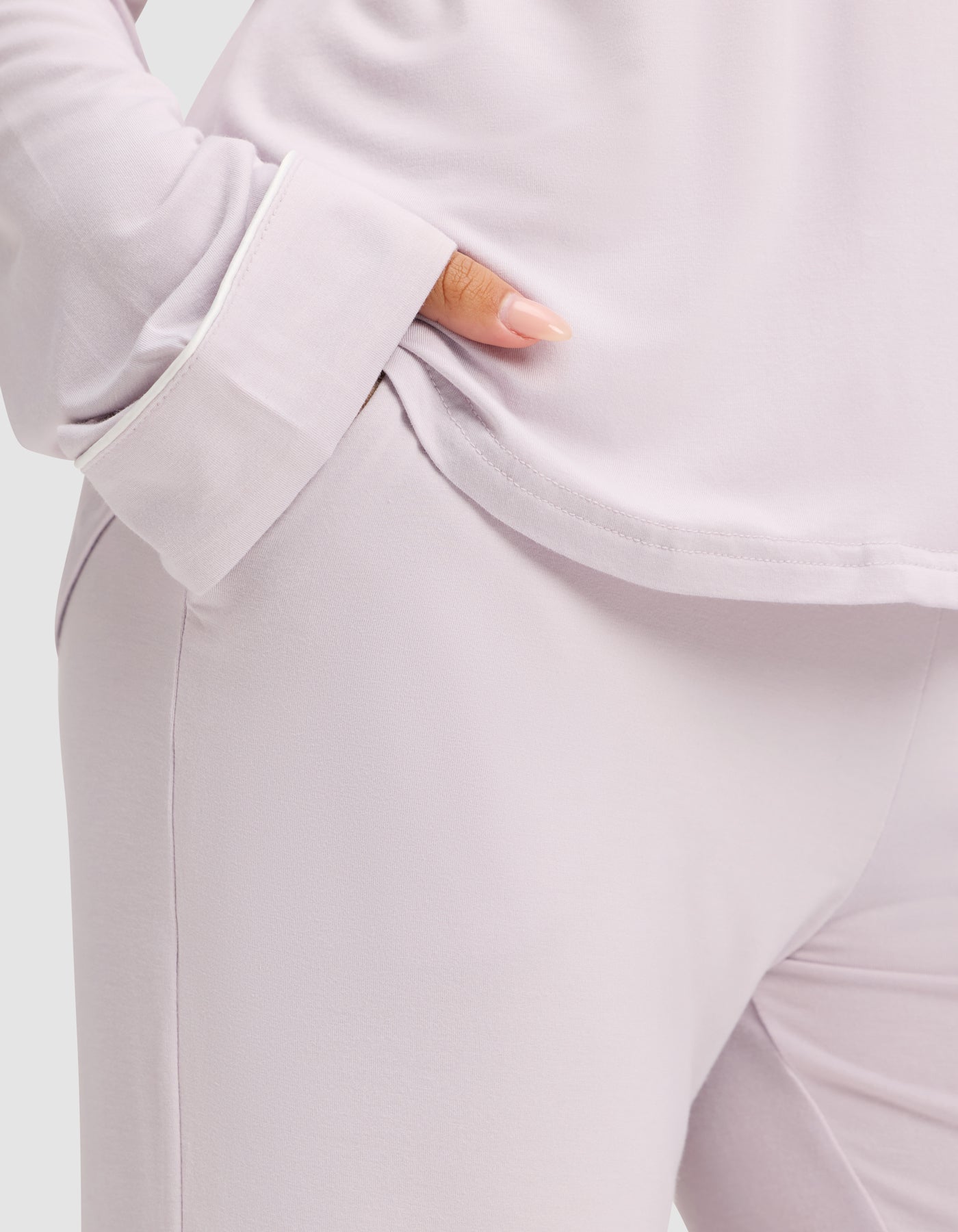 A person models the Cozy Earth Women's Bamboo Stretch-Knit Long Sleeve Pajama Set in light lavender, hand in pocket, with the torso and upper legs visible to showcase the soft, comfortable fabric. 