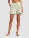A person stands barefoot wearing Cozy Earth's Women's Bamboo Stretch-Knit Pajama Short in light green and white vertical stripes with a drawstring waist and pockets, shown from mid-torso to feet against a plain background.|Color:Market Stripe in Julep
