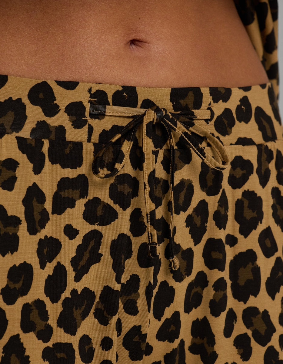 Close-up of a person’s midsection wearing Cozy Earth Women’s Bamboo Stretch-Knit Pajama Pant in tan and black leopard print, featuring a drawstring waistband and visible navel.