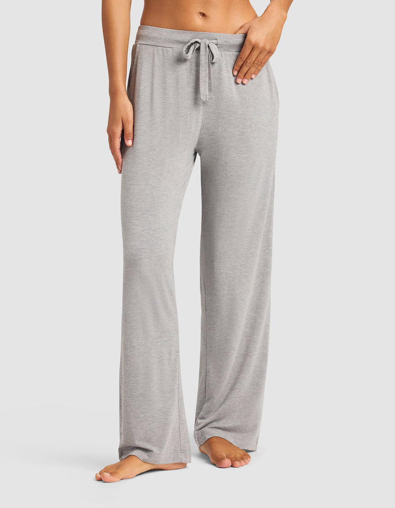 A woman models the Cozy Earth Women's Bamboo Stretch-Knit Pant in light gray, shown barefoot from the waist down against a plain white background. Only her lower torso and legs are visible.