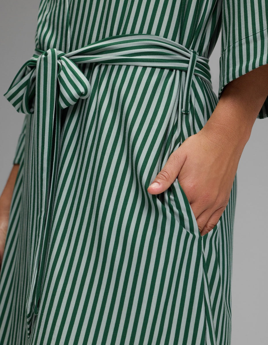 A person wearing a green and white striped Cozy Earth Women’s Bamboo Stretch-Knit Kimono Robe with a tie waist and a visible side pocket.