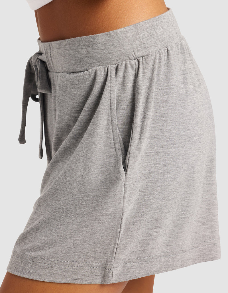 A close-up side view of a person wearing Cozy Earth Women's Bamboo Stretch-Knit Shorts in light gray, featuring a soft knit fabric, elastic waistband with drawstring, and side pocket for a comfortable, casual look.
