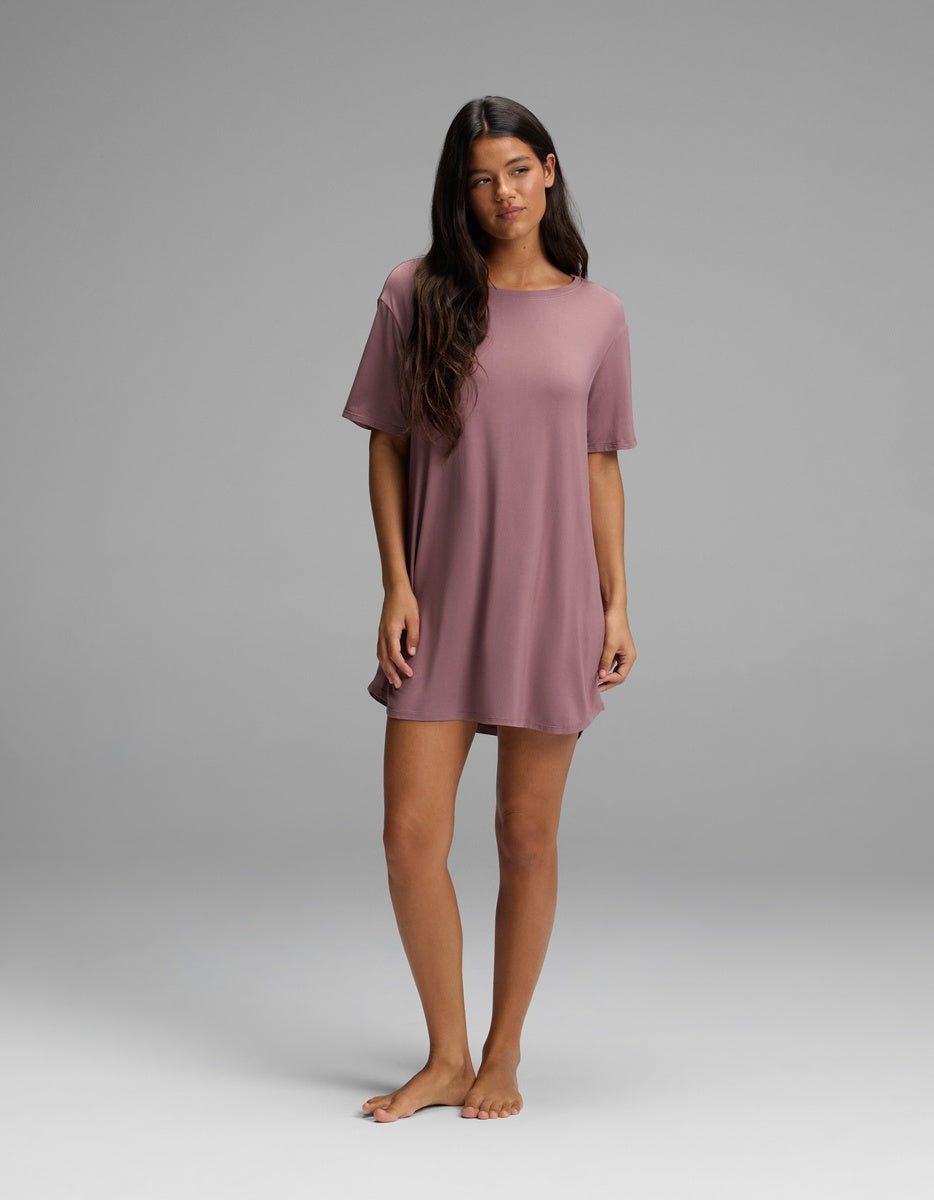 A woman wearing a mauve, short-sleeved, knee-length Cozy Earth Women’s Bamboo Stretch-Knit Sleep Dress.
