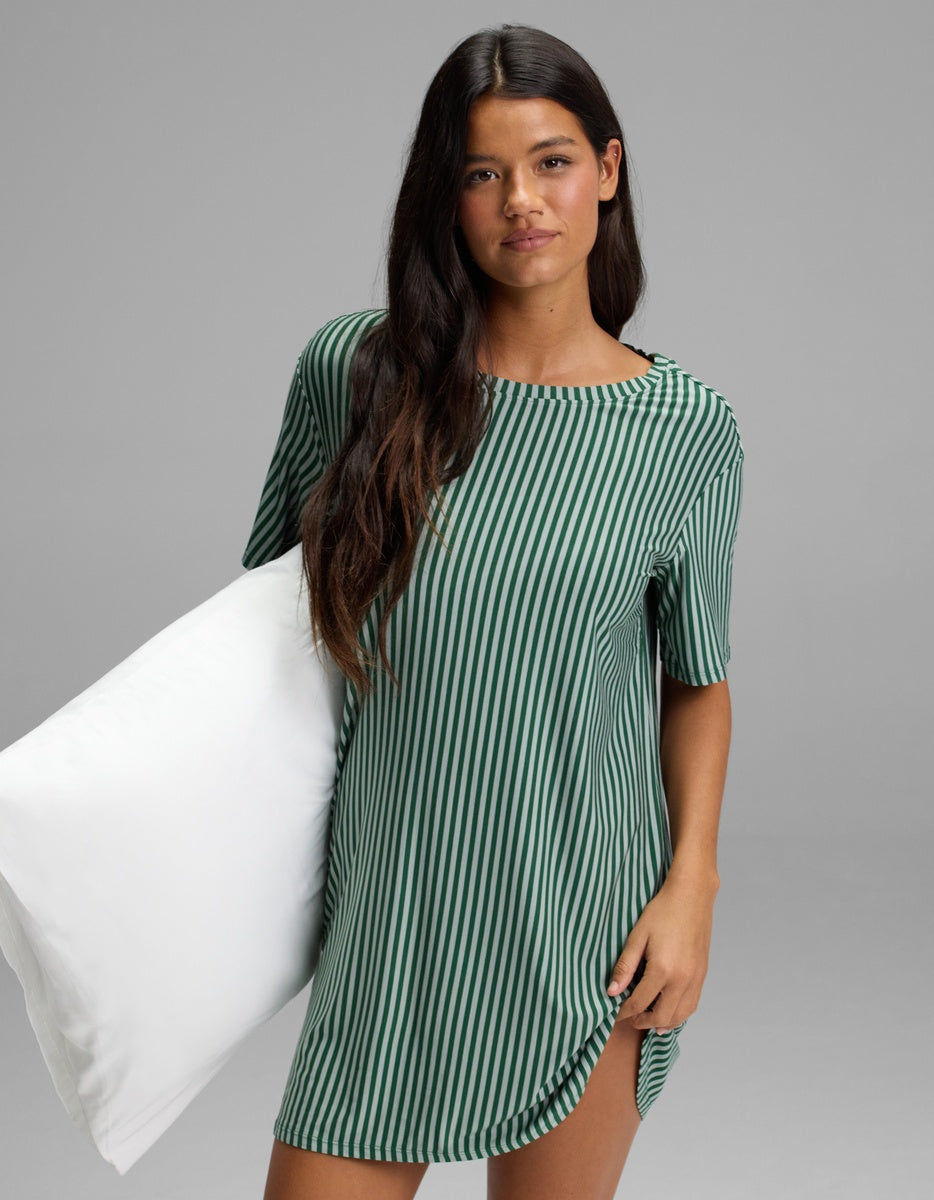 A person wearing a dark green and white vertical striped Cozy Earth Women’s Bamboo Stretch-Knit Sleep Dress, holding a white pillow.