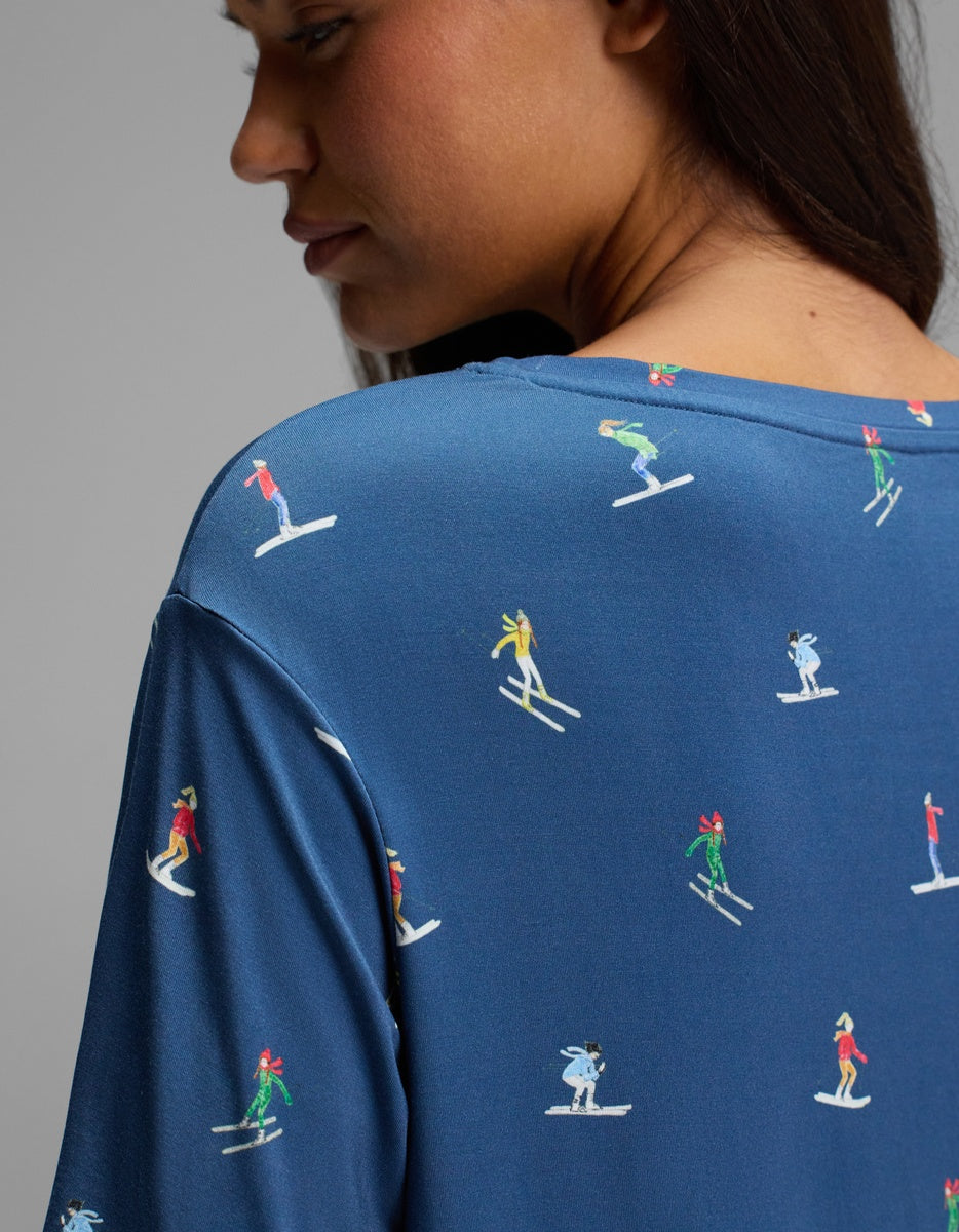 A blue Cozy Earth Women’s Bamboo Stretch-Knit Sleep Dress featuring a repeating pattern of people skiing.