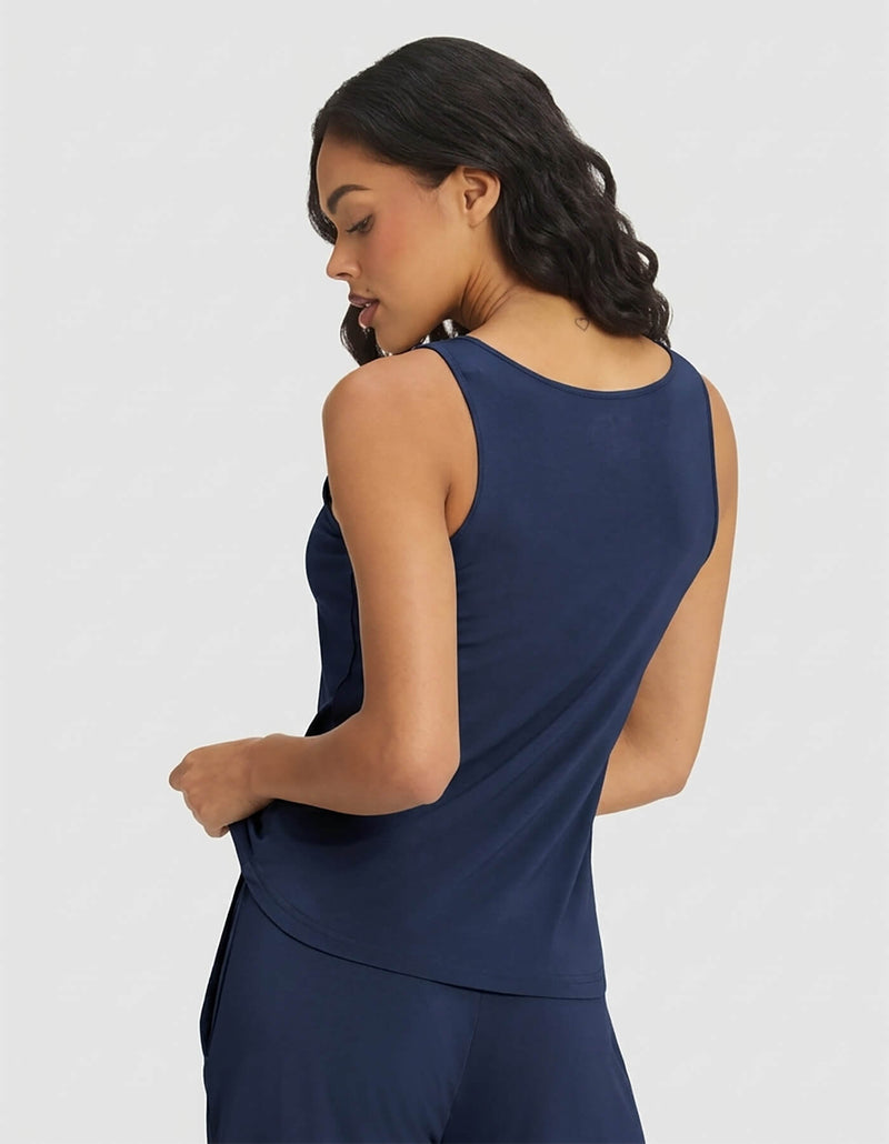A woman with wavy dark hair is seen from the back wearing the Cozy Earth Women's Bamboo Stretch-Knit Tank & Short Set in navy blue, posed against a light gray background.
