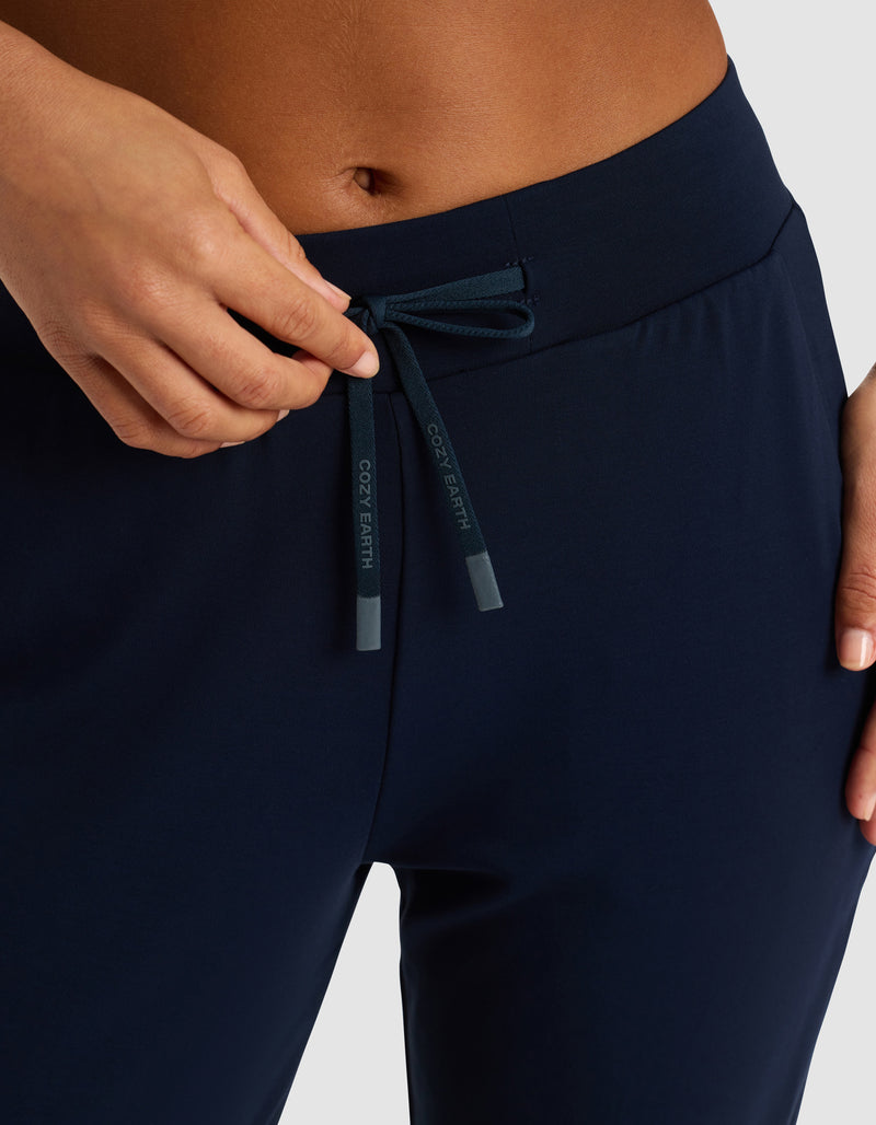 Close-up of a person adjusting the drawstring at the waistband of Cozy Earth Women's Brushed Bamboo Jogger Pant in dark navy blue, with "COZY EARTH" on the tips.