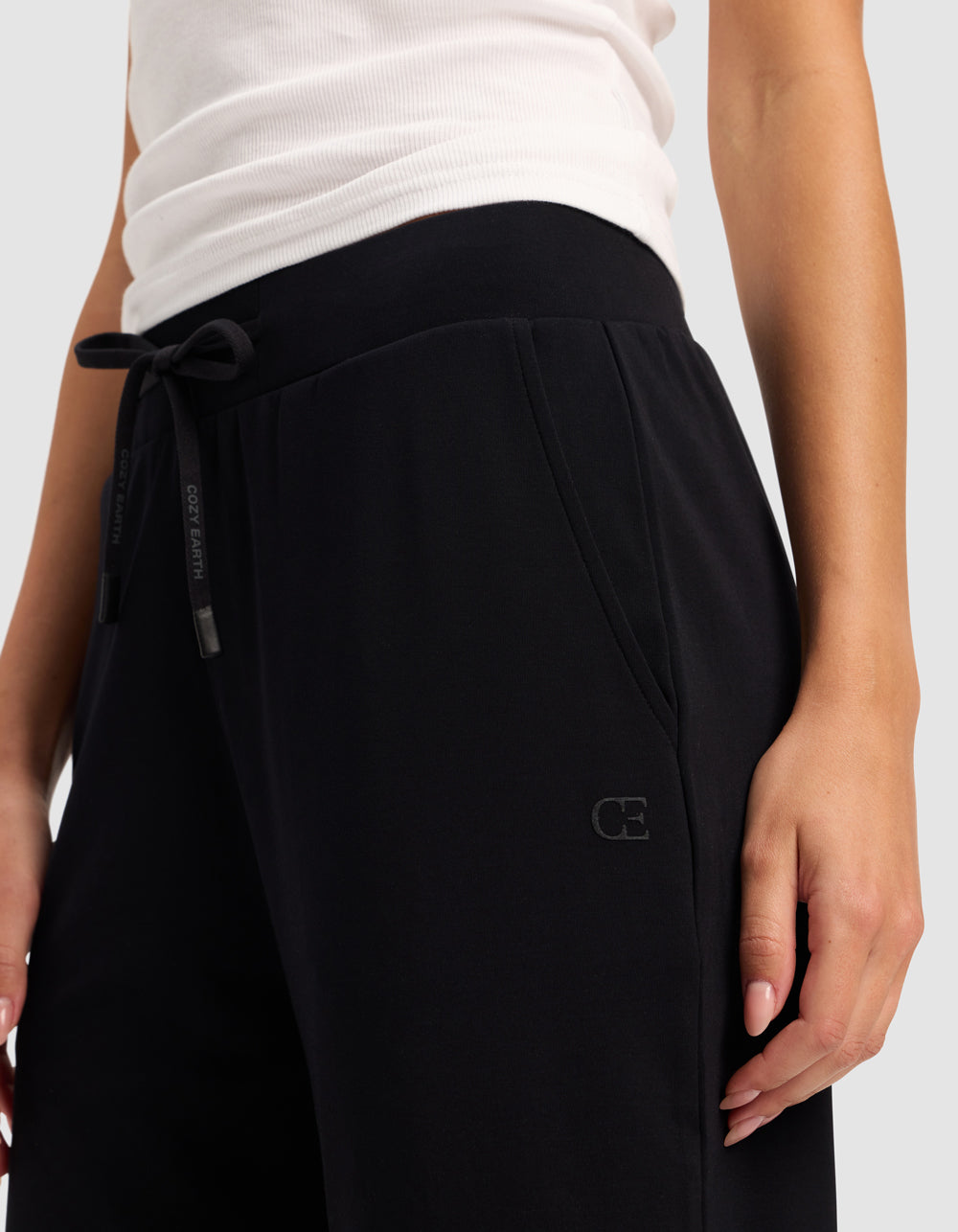 A person wearing Cozy Earth's Women's Brushed Bamboo Bermuda Shorts stands with one hand in a pocket against a plain background.|Color:Black