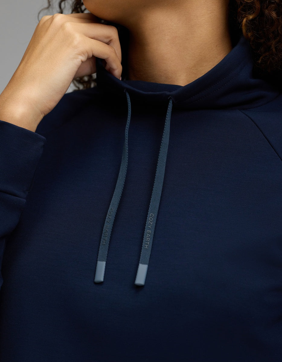A person wearing the Cozy Earth Women’s Brushed Bamboo Mock Neck in navy, holding the collar near their chin. Only the lower part of their face and hand are visible.