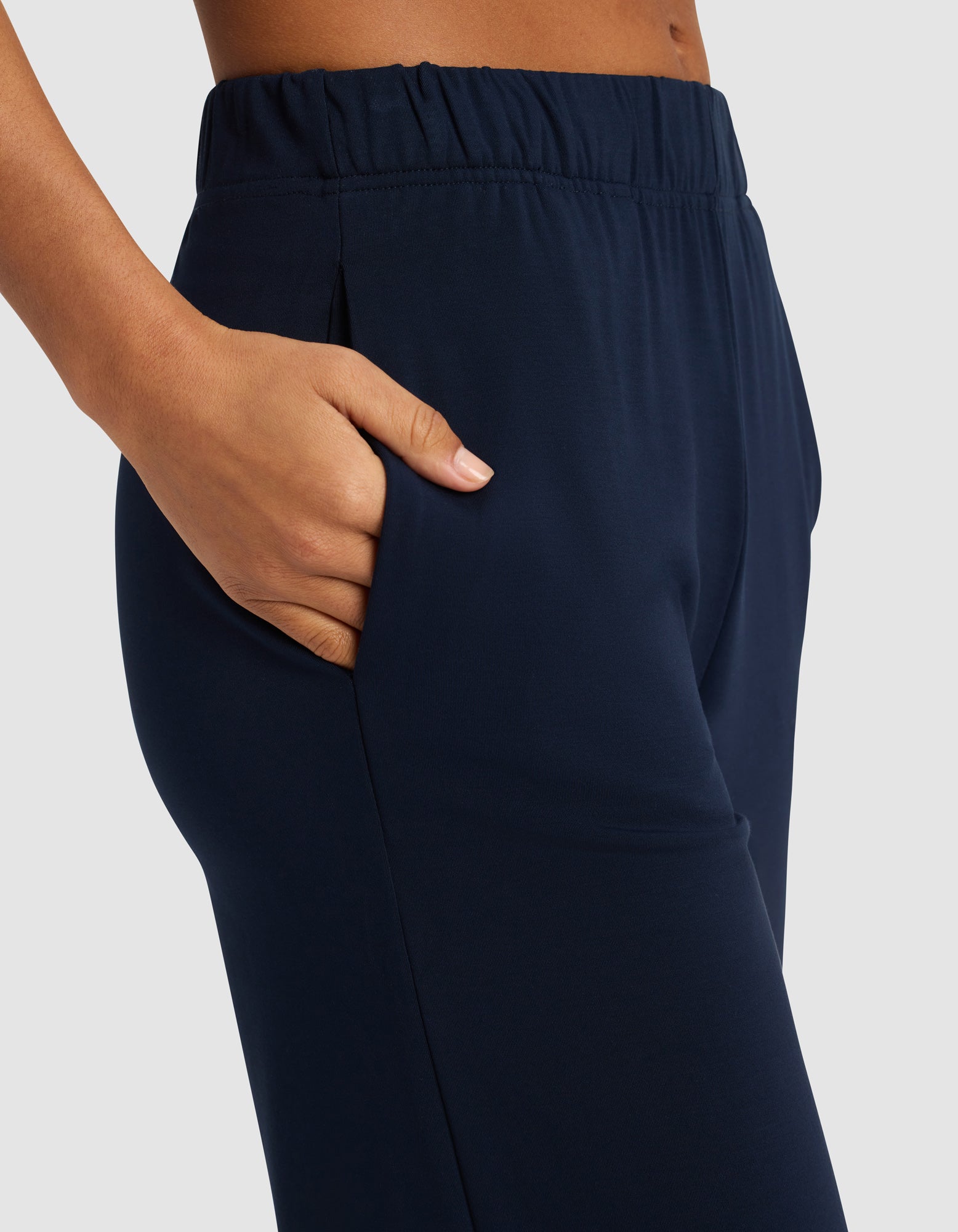 Close-up of a person wearing Cozy Earth Women's Brushed Bamboo Pull On Capri in navy blue, featuring an elastic waistband and hand-in-pocket pose against a plain light background.|Color:Navy