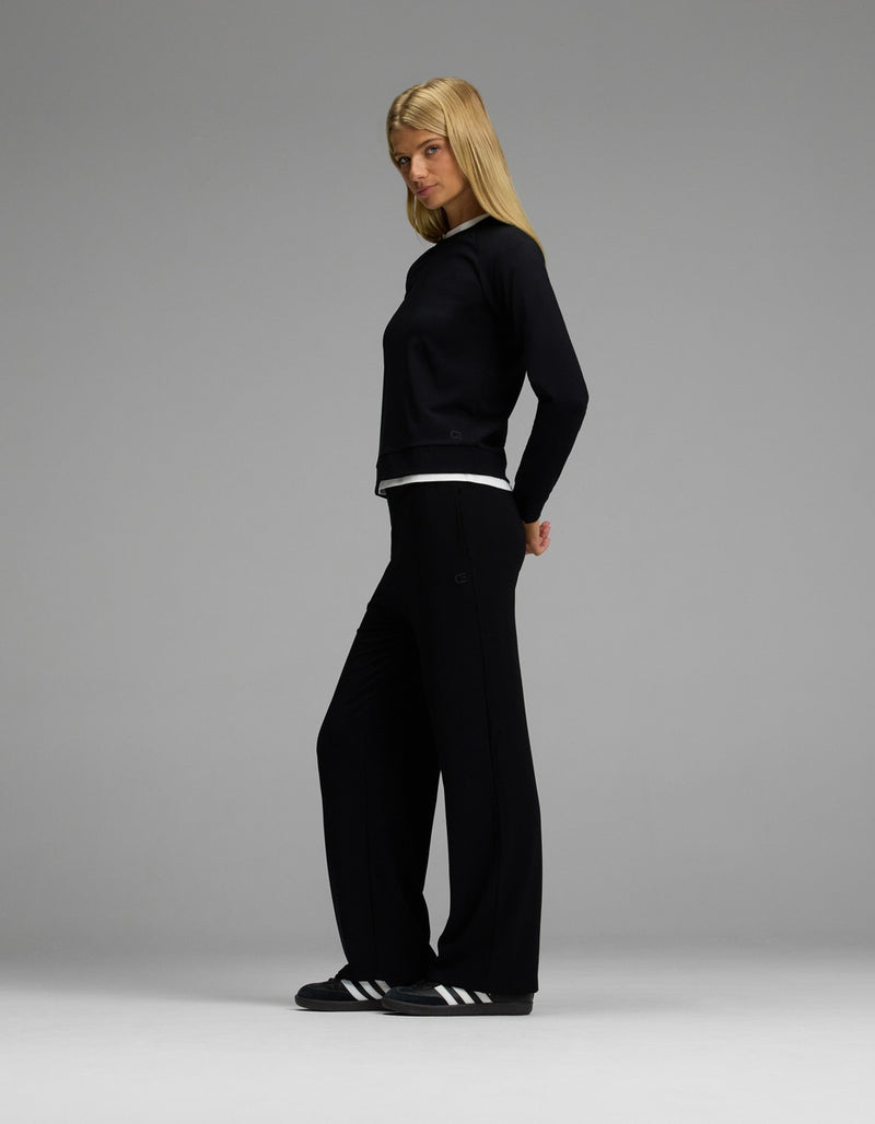 A woman with straight blonde hair stands in profile against a gray background, wearing the Cozy Earth Women’s Brushed Bamboo Wide Leg Pull On Pant & Pullover Crew Set in black.