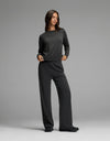 A woman stands in a relaxed pose against a plain gray background, wearing the Cozy Earth Women’s Brushed Bamboo Wide Leg Pull On Pant & Pullover Crew Set in charcoal.|Color:Charcoal