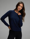A woman with long brown hair wears the Cozy Earth Women’s Brushed Bamboo Pullover Crew in navy blue, paired with black leggings, standing against a plain gray background.|Color:Navy