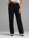 A person stands against a gray background—only the lower body is visible—wearing Cozy Earth’s Women’s Brushed Bamboo Wide Leg Pull-On Pant in black, paired with a white cropped top and white sneakers.|Color:Black