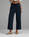 A person is wearing the Cozy Earth Women’s Chelsea Cropped Pant in Eclipse, featuring a drawstring waist and wide-leg silhouette, paired with a light gray cropped top and brown sandals. Only the lower torso and legs are visible, standing against a plain gray background.|Color:Eclipse