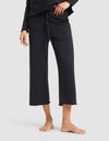 A person is shown barefoot against a plain background, wearing the lower half of Cozy Earth's Women's Chelsea Cropped Pant in black, paired with a matching black top. Only the pants and a portion of the top are visible. |Color:Jet Black