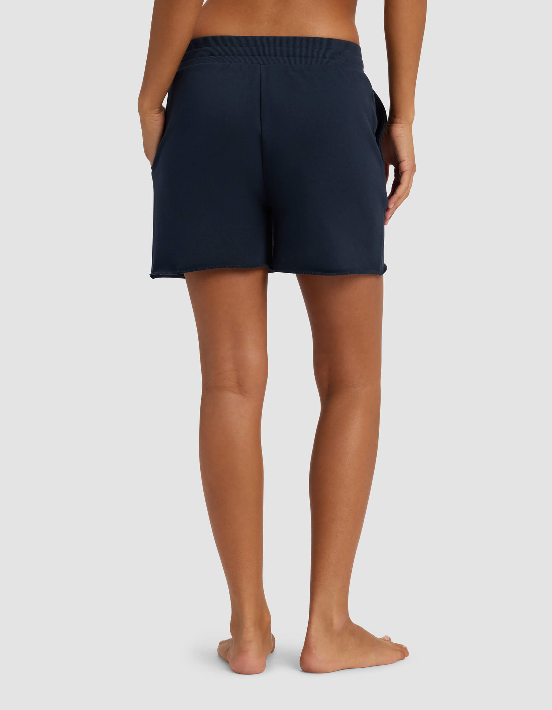 A woman wearing Cozy Earth's Women's Chelsea Short in navy blue, featuring a drawstring waist and raw edges.