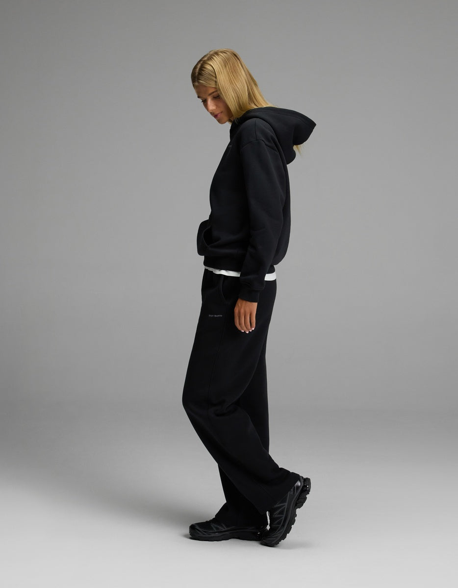 A person with long blond hair wears the Women’s CityScape Hoodie & Wide Leg Pant Set by Cozy Earth, standing sideways against a plain gray background.