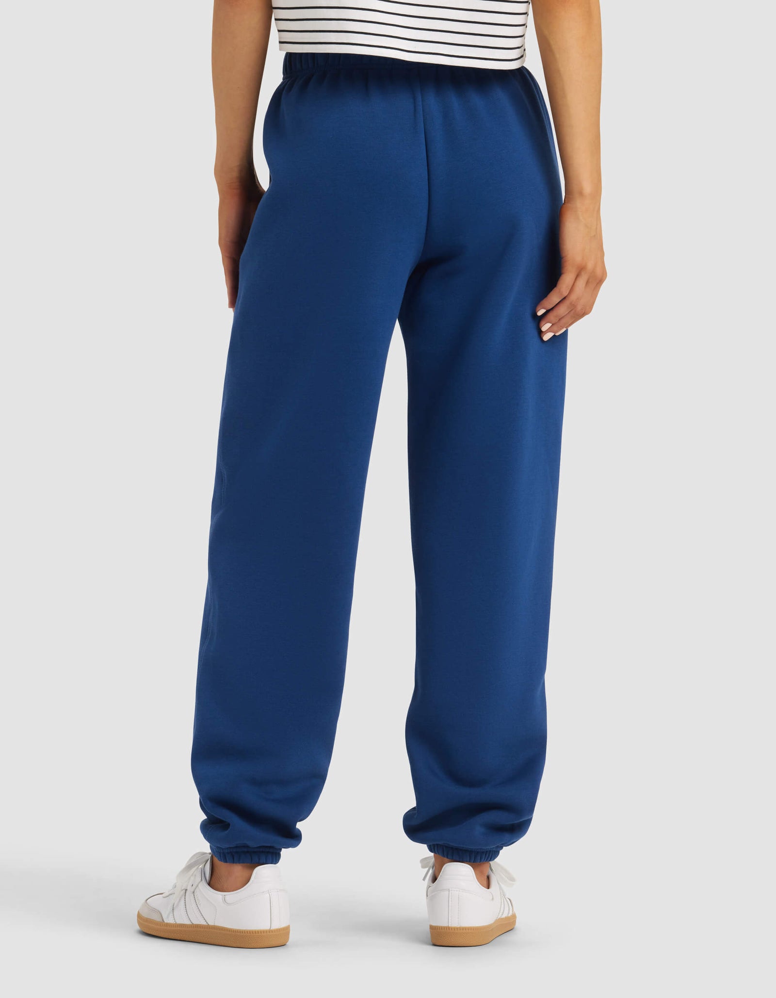 A person stands with their back to the camera, wearing a striped shirt, white sneakers, and Cozy Earth Women's Cityscape 2.0 Sweatpant featuring an elastic waistband and cuffs.