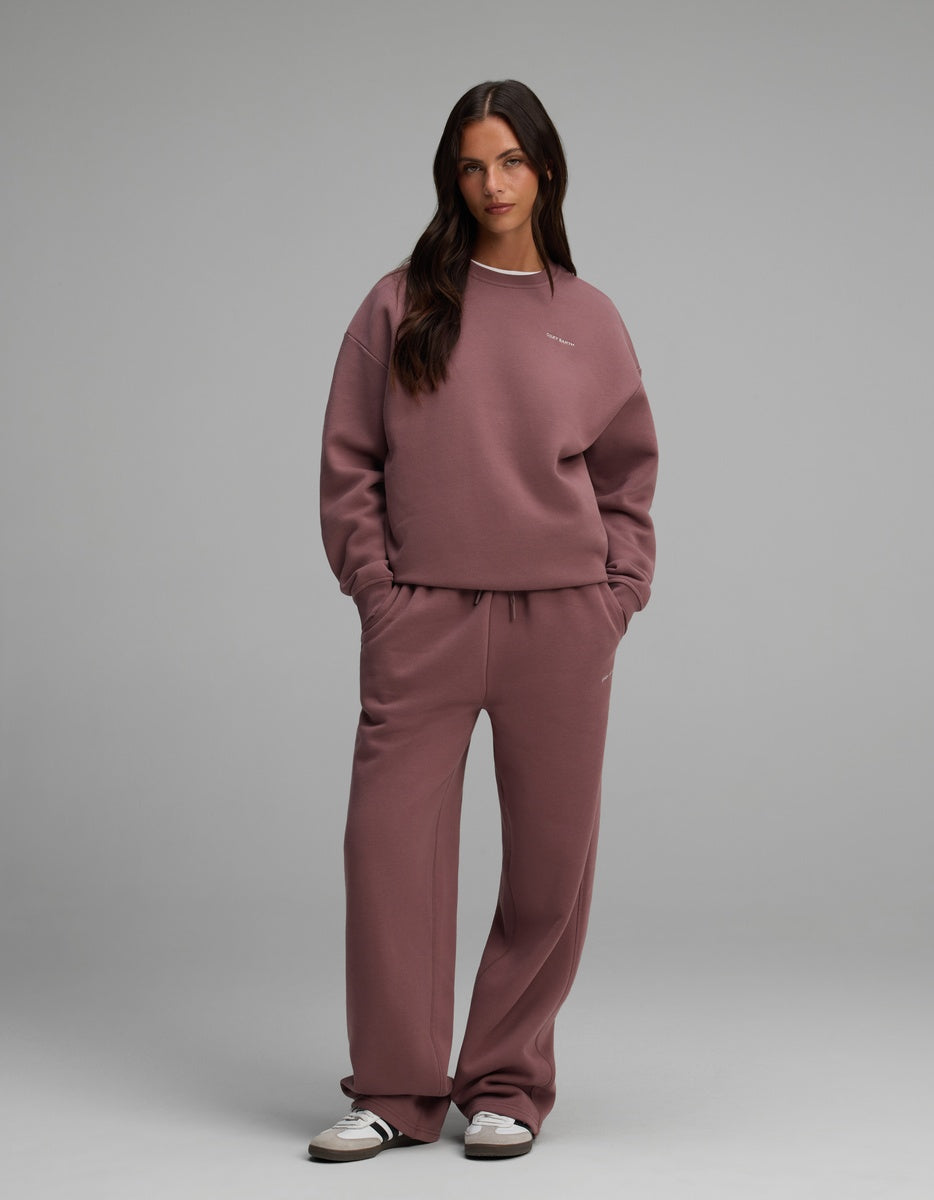 A woman wearing a mauve Cozy Earth Women’s CityScape Crewneck and matching loose-fitting sweatpants.